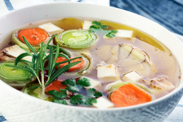 Broth with carrots, onions various fresh vegetables in a pot - colorful fresh clear spring soup. Rural kitchen scenery vegetarian bouillon or stock