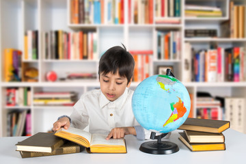 the boy studies the globe and reads the book.