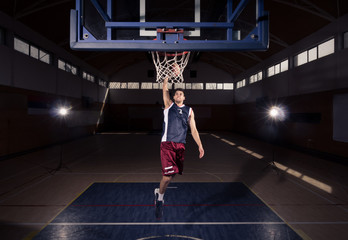basketball player, slam dunk in air, indoors dark basketball court