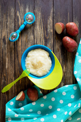 Food for kids, children's lure, organic puree from boiled potatoes in a bowl on a dark rustic wooden background