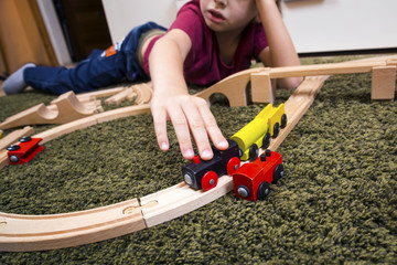 Child boy play with wooden train, build toy railroad at home or daycare.