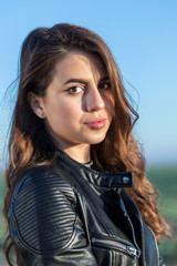 Fototapeta premium Portrait of sweet brunette girl in leather jacket looking at the camera
