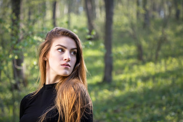 Portrait of a young blonde girl in forest looking away