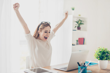 Fototapeta na wymiar Yes! Happy excited woman at home workstation triumphing with raised hands