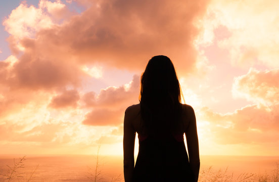 Silhouette of woman standing in the sunset. 