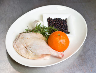 Free range raw duck leg, with herbs, orange and garlic, on a white plate. Duck wellington step by step.