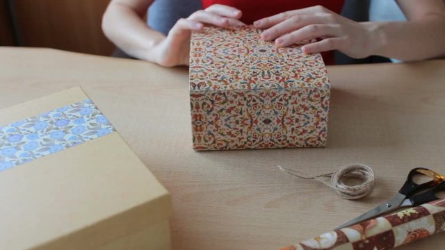 Women's hands wrap gifts on wooden table