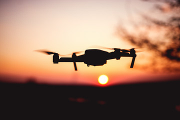 Drone flying into the sunset. Silhouette of drone against colorful sky.