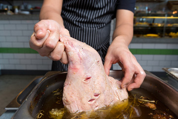 A fresh organic leg of lamb being placed in a marination tub of virgin olive oil, salt, pepper,...