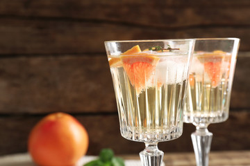 Refreshing cocktails with grapefruit slices on blurred wooden background