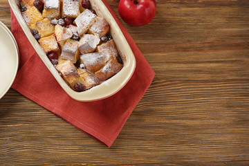 Freshly baked bread pudding in casserole dish on wooden table