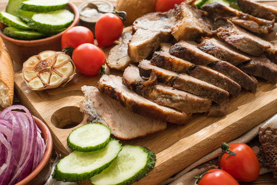 Sliced grilled meat barbecue on cutting board with vegetable .