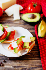 Healthy, wholesome and healthy breakfast or lunch, sandwiches with fresh avocado with spices, mozzarella cheese and tomato on a dark rustic wooden background