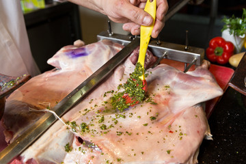 Delicious free range goat shoulder being marinated with parsley and oil, and being prepared for...