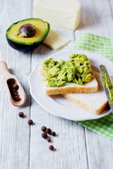 Healthy, wholesome and healthy breakfast or lunch, sandwiches with puree from fresh avocado with spices, mozzarella cheese and mineral water on a light rustic wooden background 