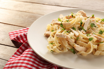 Plate with delicious Chicken Alfredo on wooden table