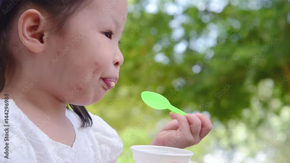 Wall mural Little asian girl eating ice cream in park
