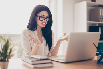 Close-up portrait of beautiful young businesswoman at a loss with glasses at office sitting at the...
