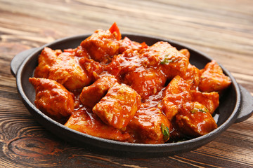 Frying pan with delicious chicken tikka masala on wooden table