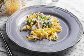 Plate of delicious pasta alfredo with chicken on table