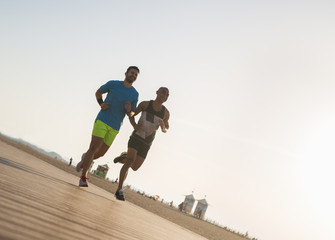 Fototapeta na wymiar Two sporty men training at bright beach in early morning.