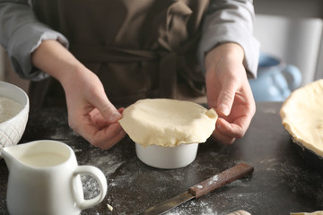 Woman making delicious chicken pot pie on kitchen table