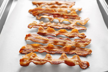 Tasty bacon slices on parchment, closeup