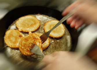 Cooking process of potato flapjacks on the pan with boiling sunflower oil close up with motion blur