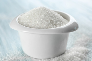 Bowl full of sugar on wooden background