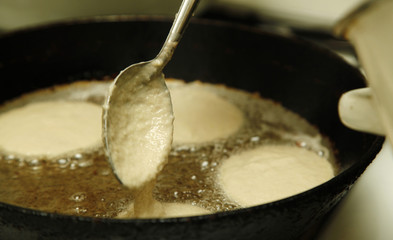 Cooking process of potato flapjacks on the pan with boiling sunflower oil close up with motion blur