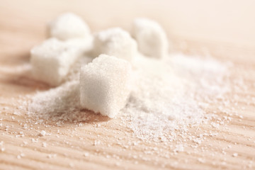 Granulated sugar and cubes on wooden background