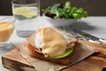 Tasty egg Benedict on wooden board