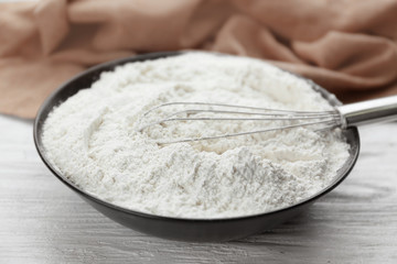 Bowl full of white wheat flour on wooden kitchen table