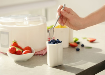 Hand of woman preparing tasty homemade yogurt in kitchen