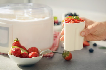 Woman with cup of tasty homemade yogurt in kitchen, closeup