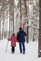 Fototapeta na wymiar Active happy healthy grandfather and granddaughter, skiing in the snowy woods on a sunny winter day