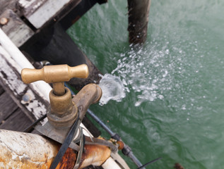 A leaking old rusty tap at a fishing cleaning station on a fishing jetty