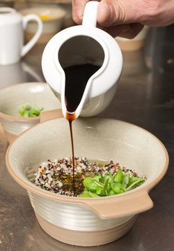 Balsamic vinegar being poured into a rustic bowl of Organic quinoa