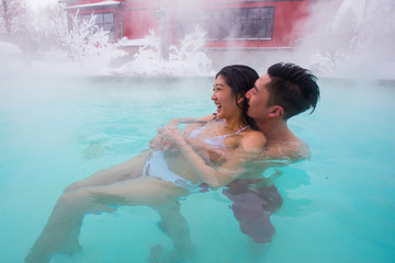 Ethnic couple relaxes in outdoor spa during winter