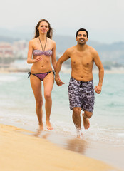 Adults running in swimwear on the sea waves