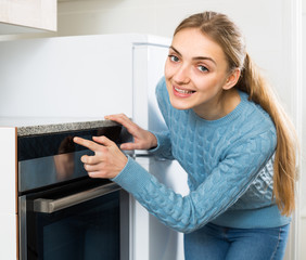 Girl near kitchen oven at home.