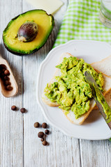 Healthy, wholesome and healthy breakfast or lunch, sandwiches with puree from fresh avocado with spices, mozzarella cheese and mineral water on a light rustic wooden background 