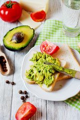 Healthy, wholesome and healthy breakfast or lunch, sandwiches with mashed potatoes from fresh avocado with spices, mozzarella cheese, tomato and mineral water on a light wooden background 