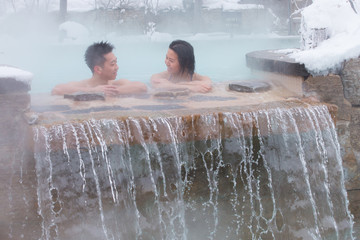 Ethnic couple relaxes in outdoor spa during winter