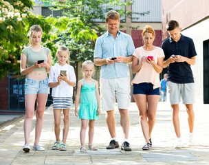 Fototapeta premium Young family with children looking at phone