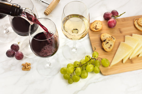 Red and white wine, cheese, bread and grapes at tasting
