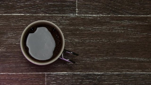 A Cup Of Strong Black Coffee With Foam On A Brown Table