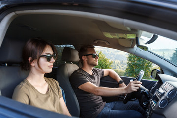 Naklejka premium Young couple smiling, sitting in car, enjoying mountains view.