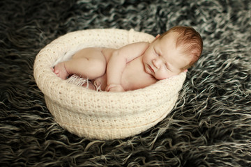 Newborn baby sleeping on fur in the basket