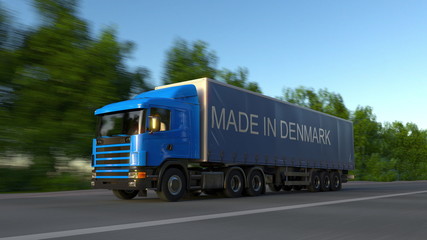 Speeding freight semi truck with MADE IN DENMARK caption on the trailer. Road cargo transportation. 3D rendering